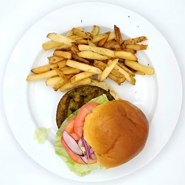 A veggie burger with lettuce, tomato, and red onion, served with a side of fries.