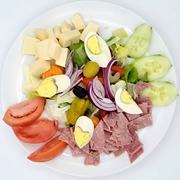 A chef salad with lettuce, tomatoes, cucumbers, cheese, eggs, olives, onions, and deli meat.